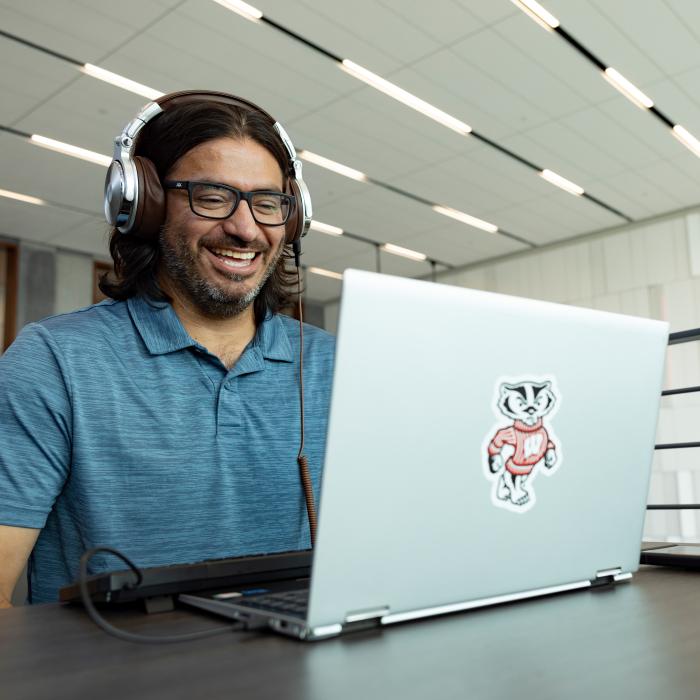 UW-Madison OUD student working remotely smiling at his laptop, in a meeting