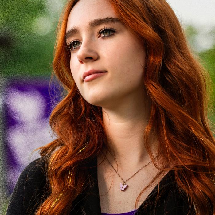 A woman with red hair looks off into the distance.