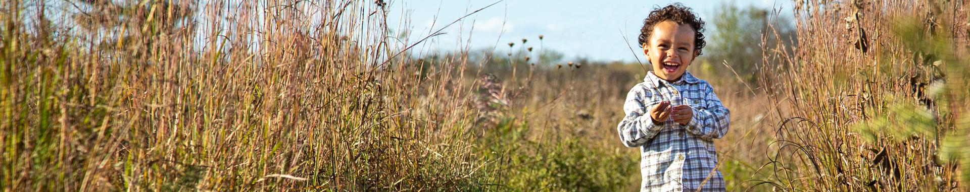 Panoramic photo of smiling young boy in a field located within Mississippi Valley Conservancy land