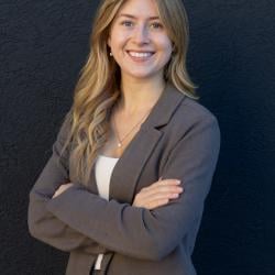 Woman smiling against a dark grey background.
